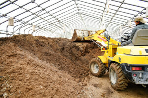 ビニールハウスの中、ホイールローダーで自家製堆肥を撹拌している